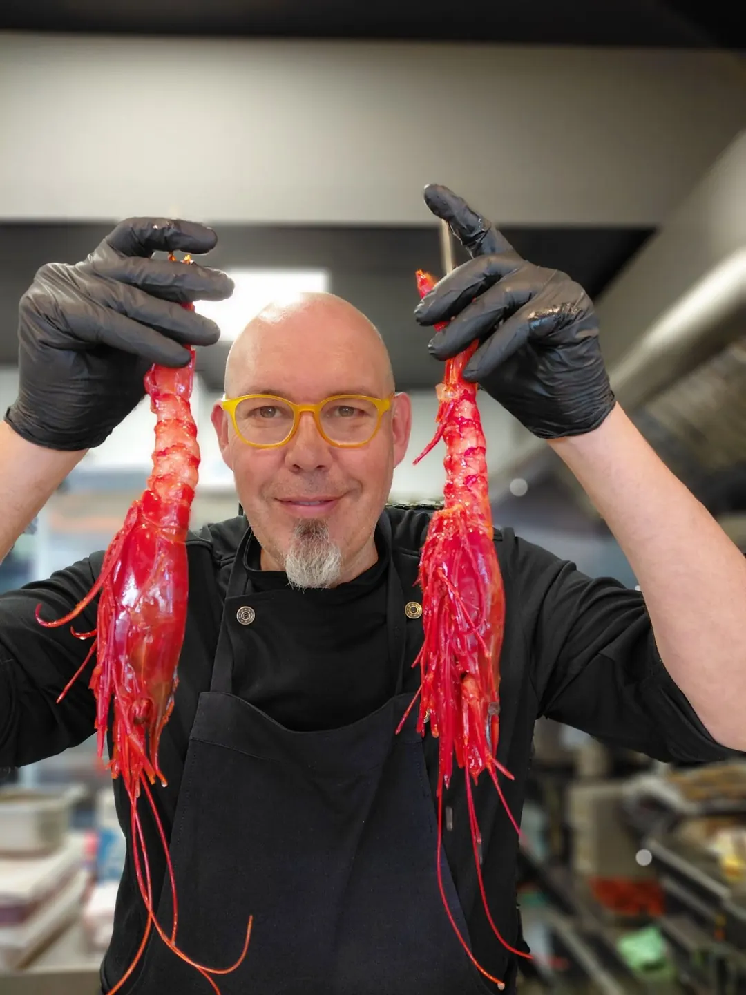 Óscar in the kitchen, holding up two carabinero prawns