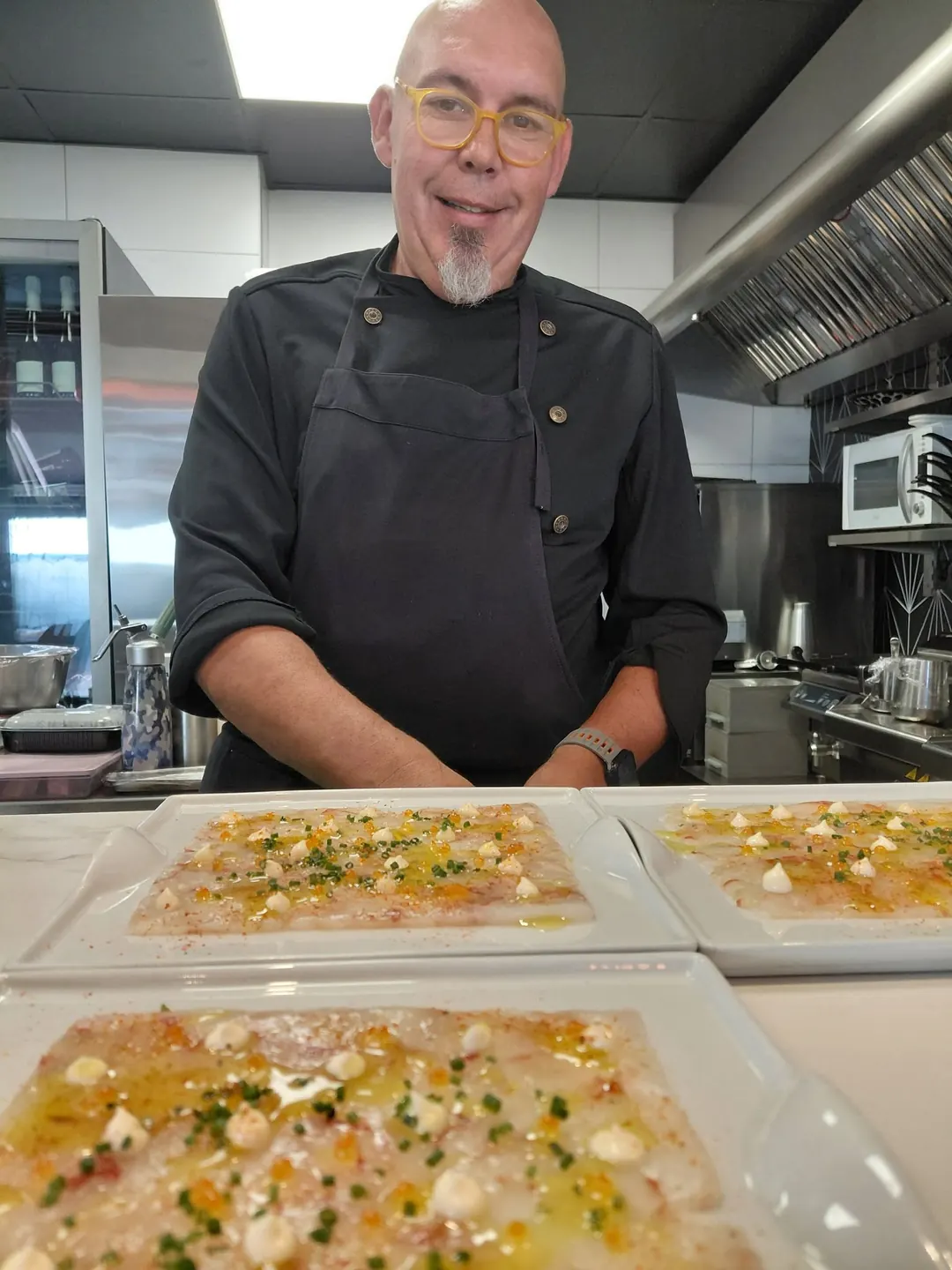 Óscar behind a counter of carpaccio plates, ready to serve