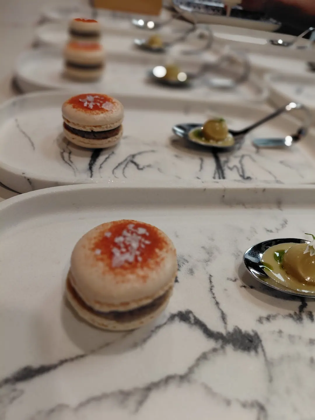 Macarons and small bites lined up on marble plates